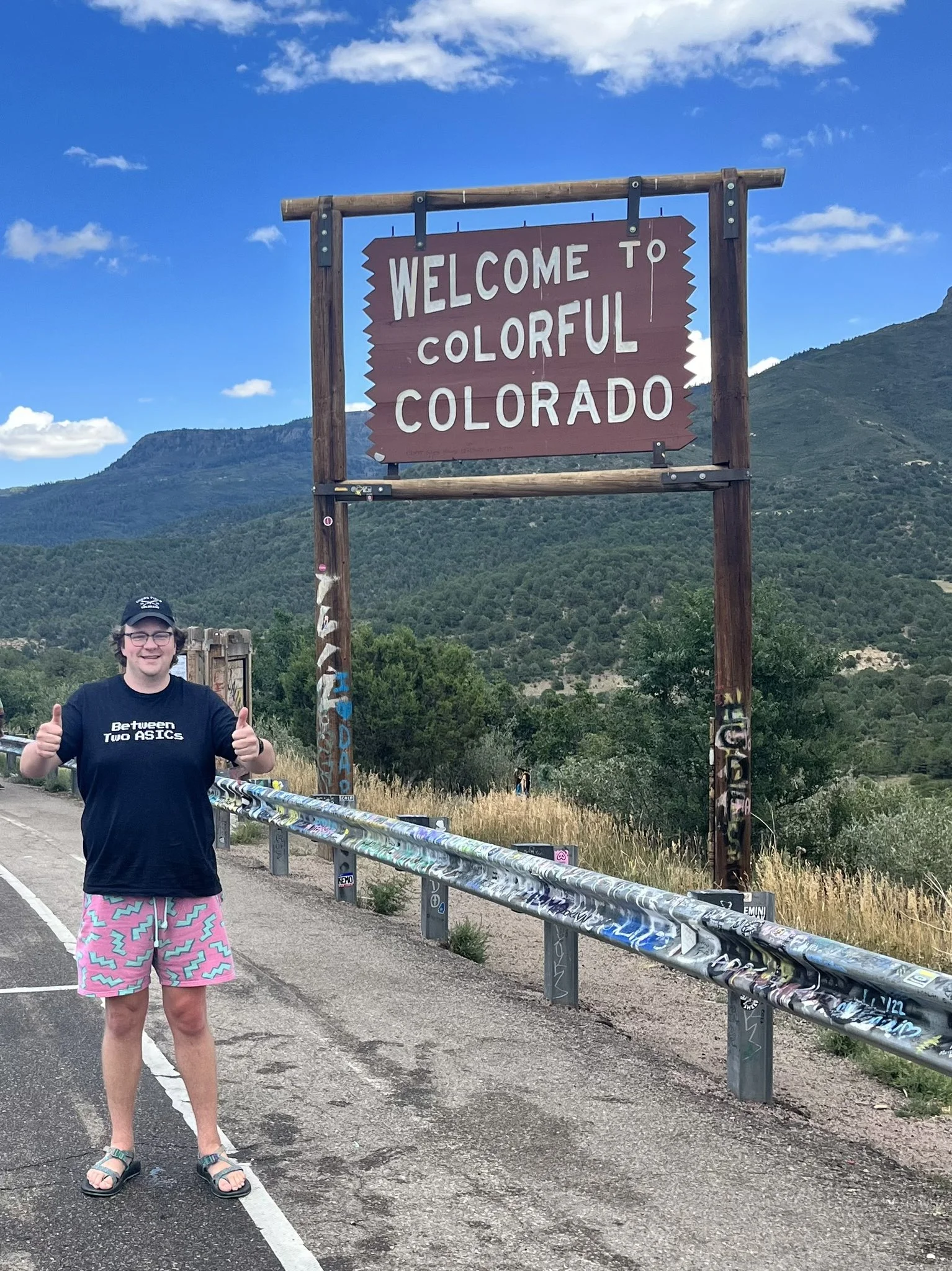 A man standing next to a 'Welcome to colorful Colorado' sign